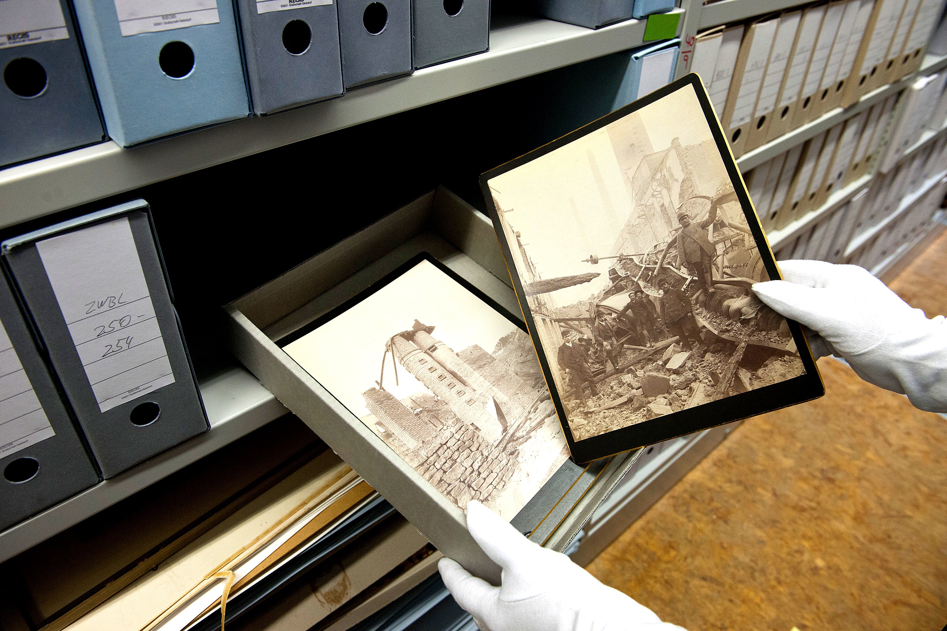 Hände mit Handschuhen nehmen historisches Bildmaterial aus einem Schuber