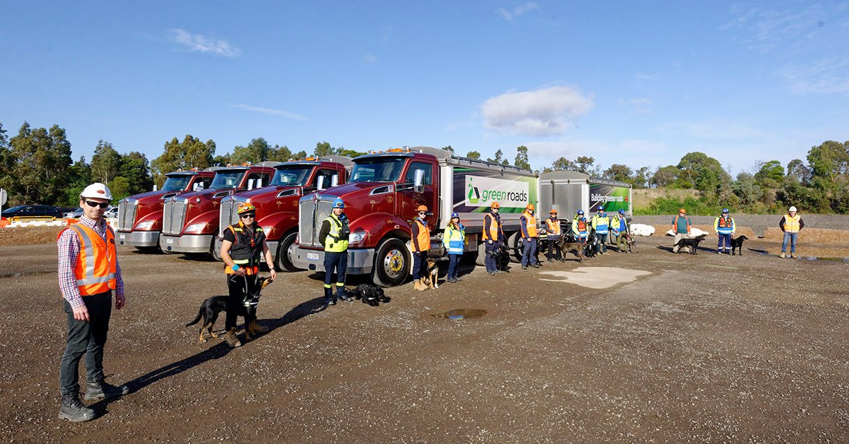 Eine Gruppe Freiwilliger mit ihren Rettungshunden vor Lastwagen