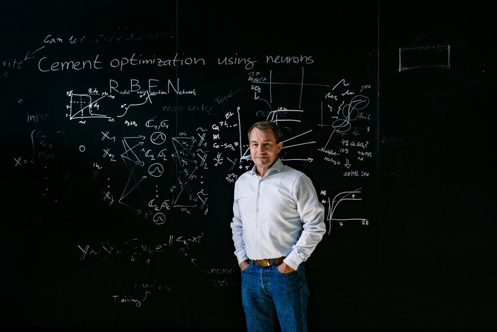 A man stands in front of a blackboard with formulae 