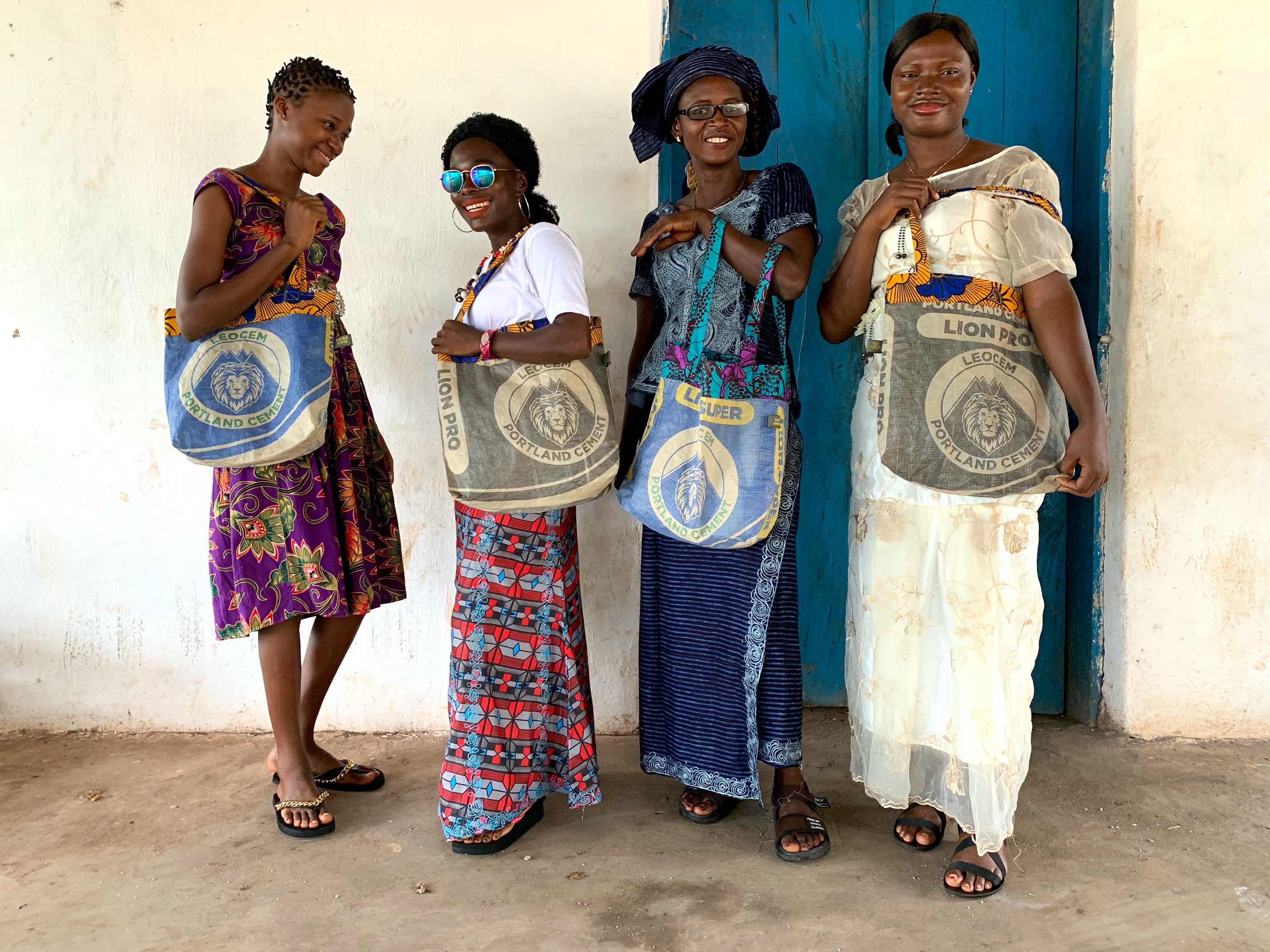 Vier Frauen aus Sierra Leone mit bunten Taschen, auf den Taschen sind Löwen abgebildet