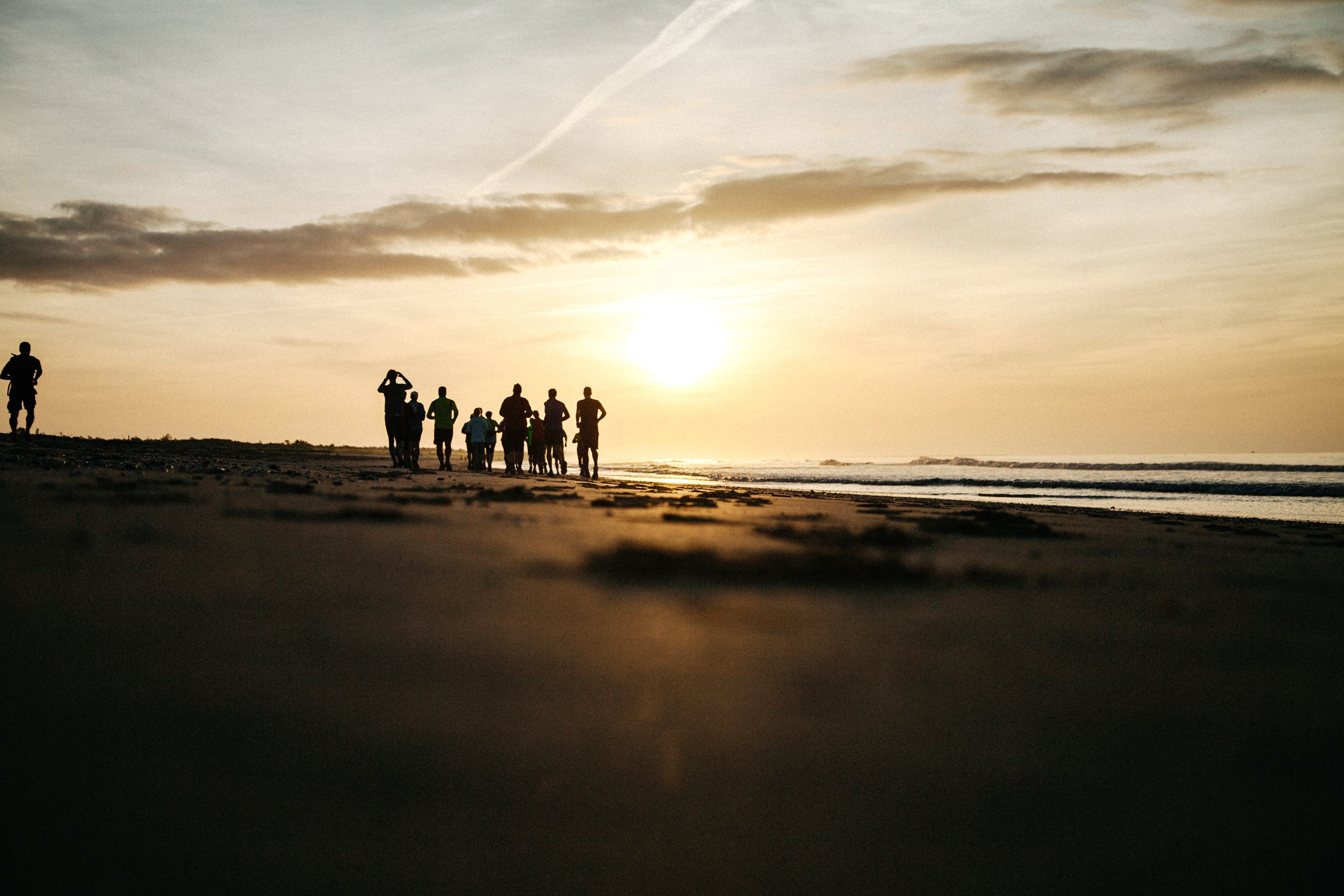 In der Ferne beobachtet eine Gruppe von Menschen den Sonnenuntergang über dem Meer