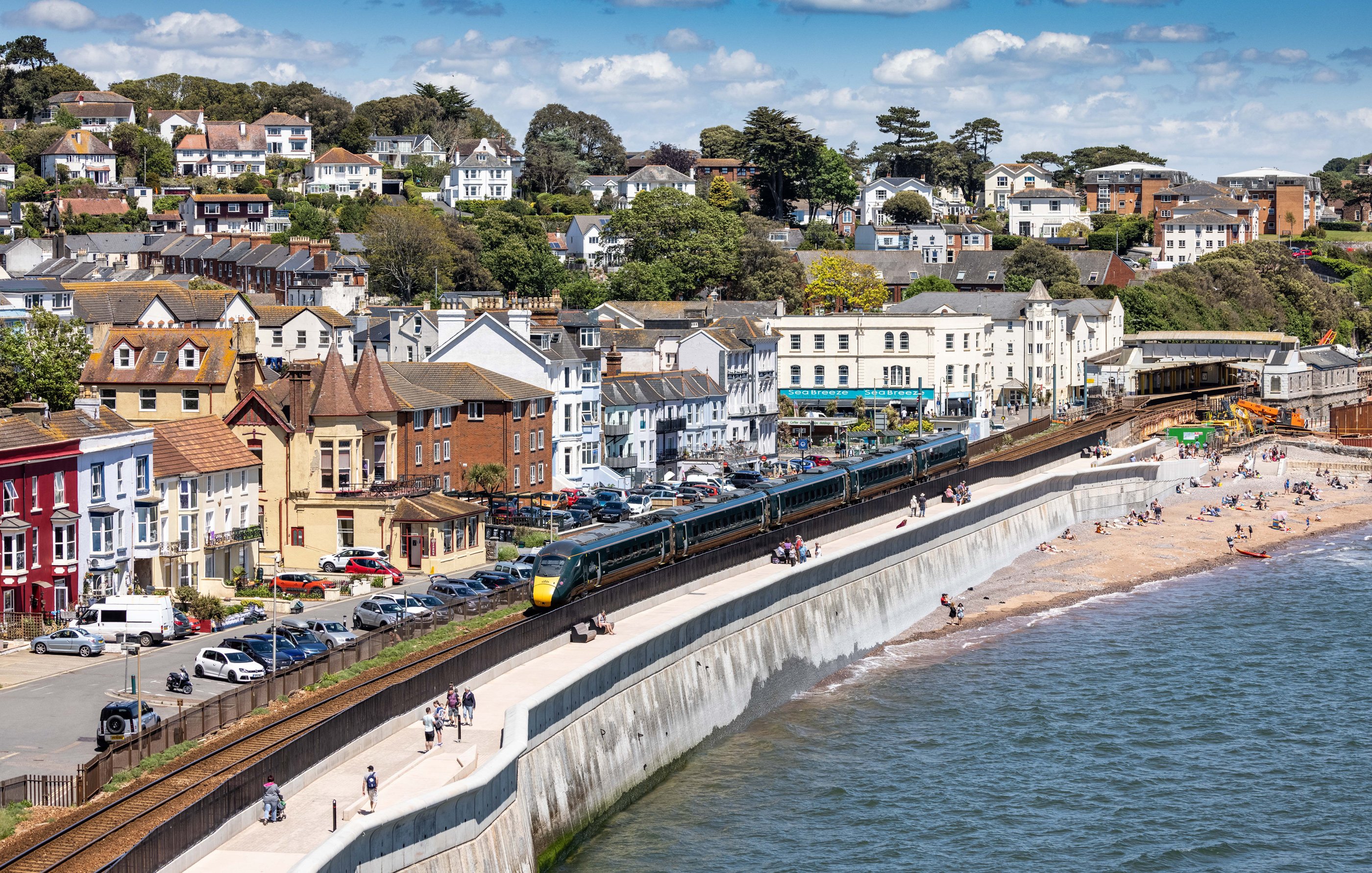 A seafront promenade, sea and land are separated by a train track