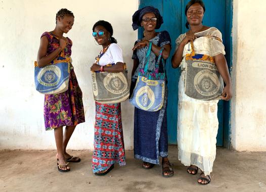 Vier Frauen aus Sierra Leone mit bunten Taschen, auf den Taschen sind Löwen abgebildet